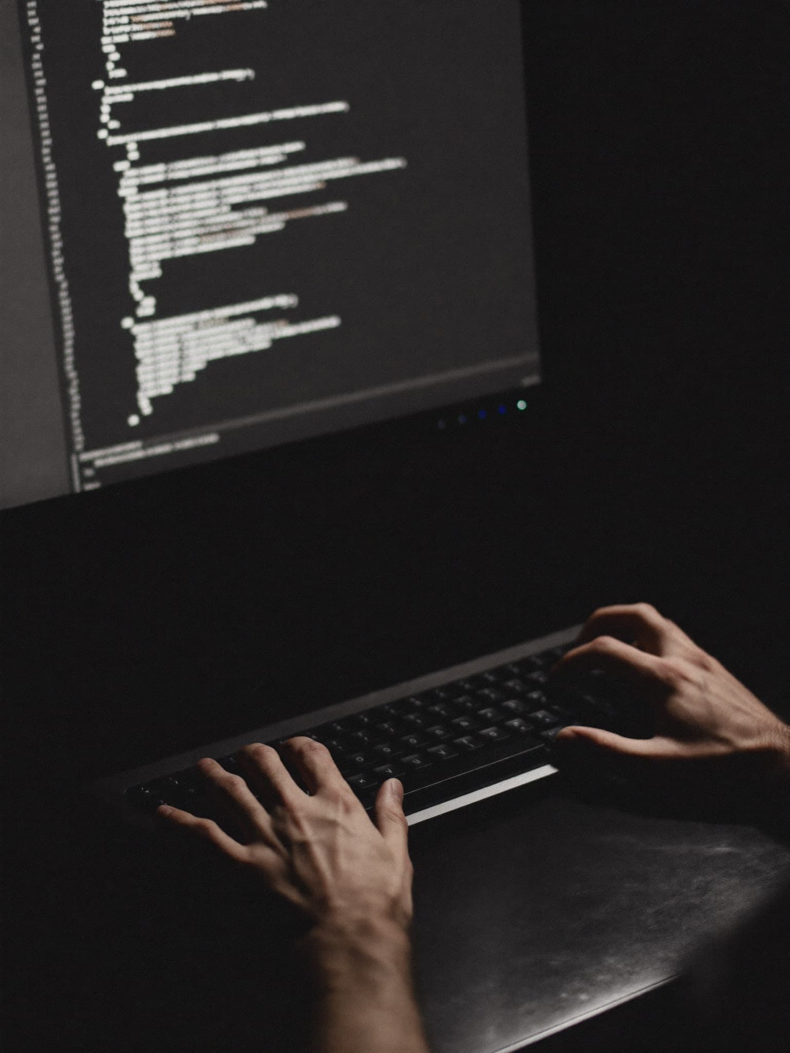 Developer typing code at a keyboard in a dark room